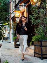 A lady wears a tweed jacket and a skirt.